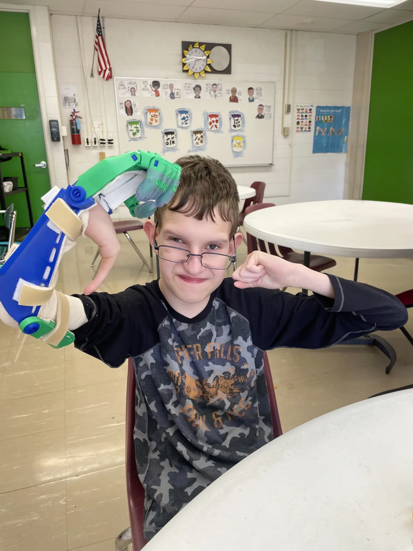 A young boy smiling while flexing both biceps with attached fabr