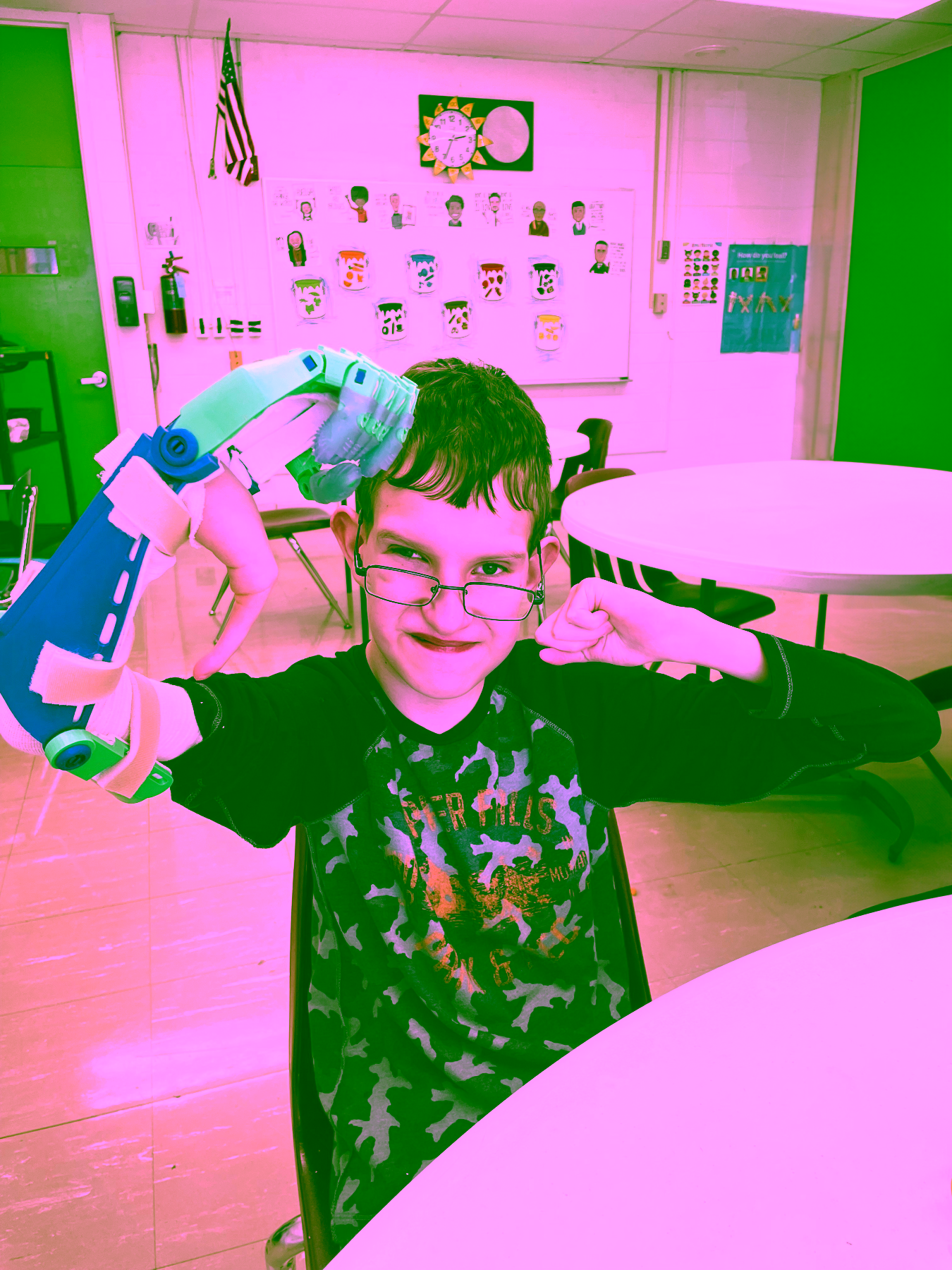 A young boy smiling while flexing both biceps with attached fabr