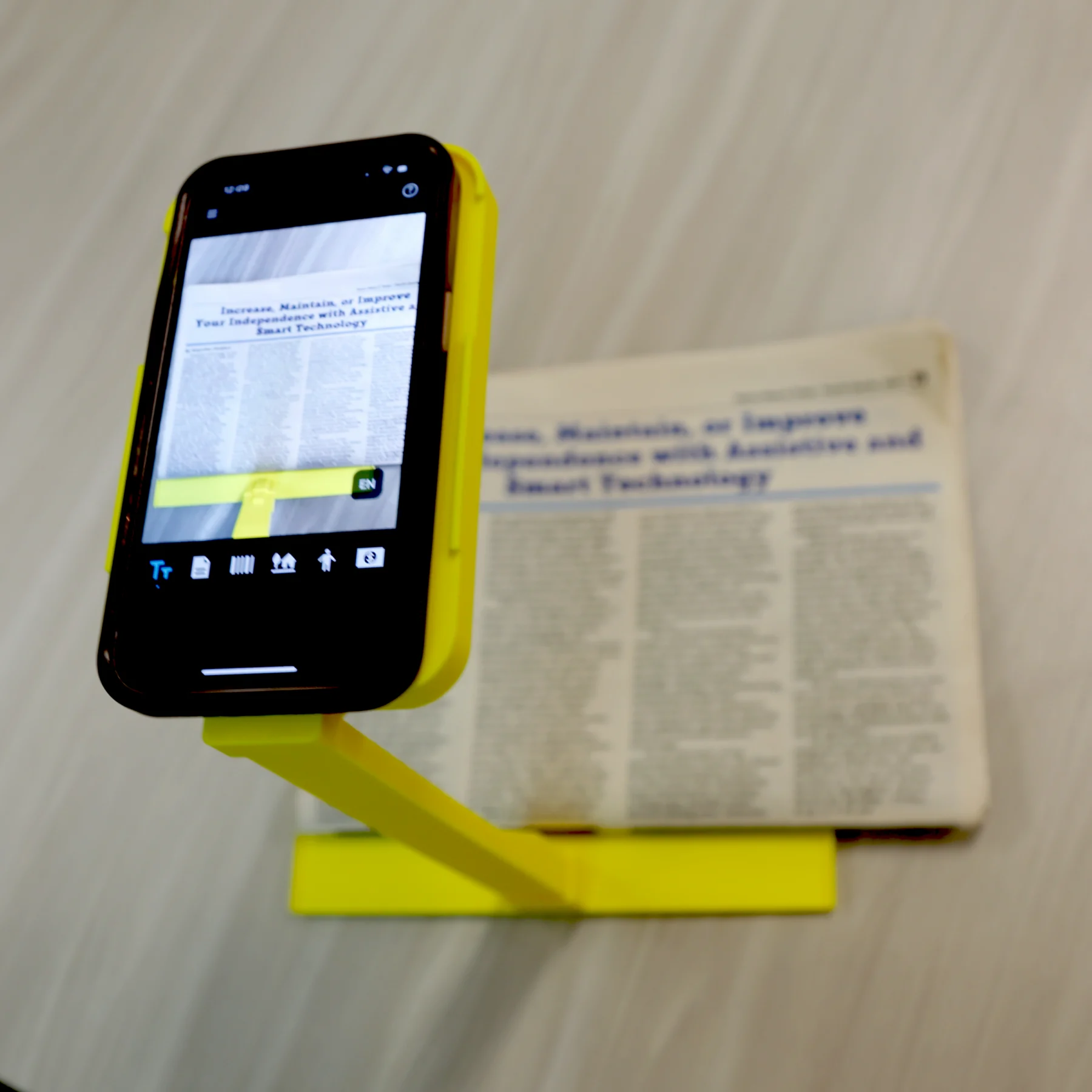 Phone stand in use using seeing AI to read a newspaper
