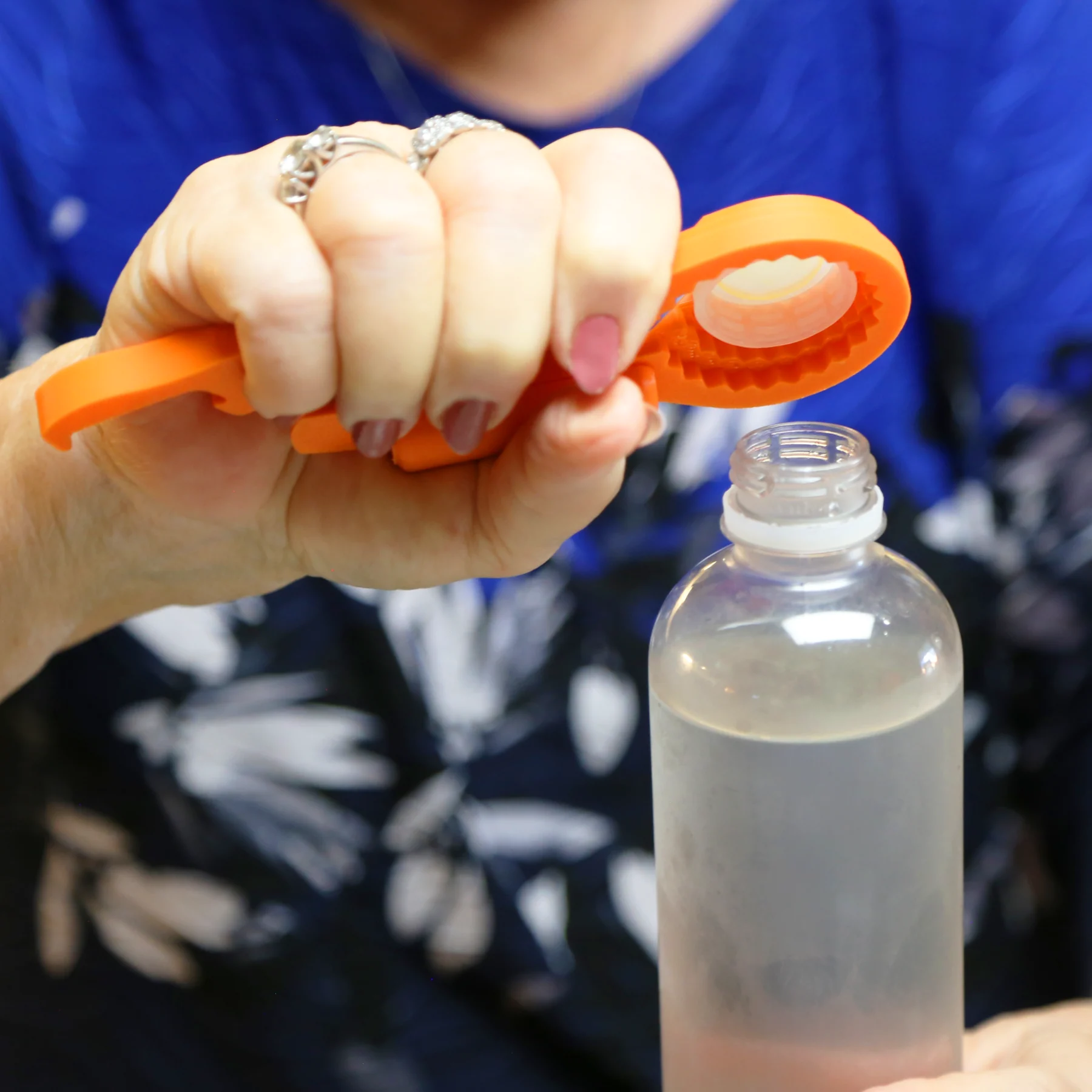 Woman taking off cap of water bottle using the Universal Bottle Opener