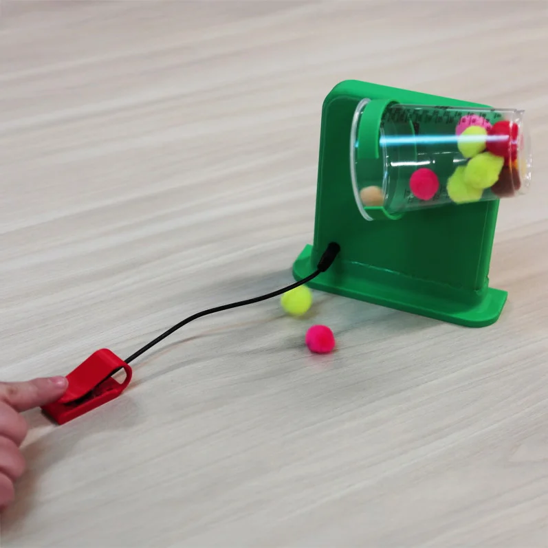 Pouring Device button in use spilling pom poms on the table