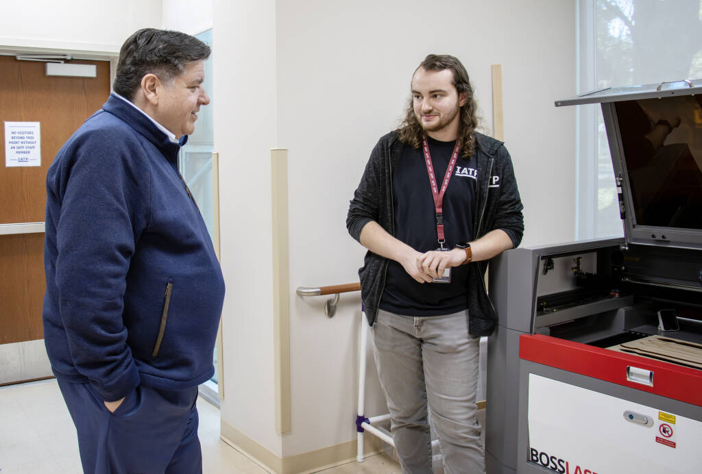 IATP Maker staff showing Governor Pritzker laser cutter at IATP