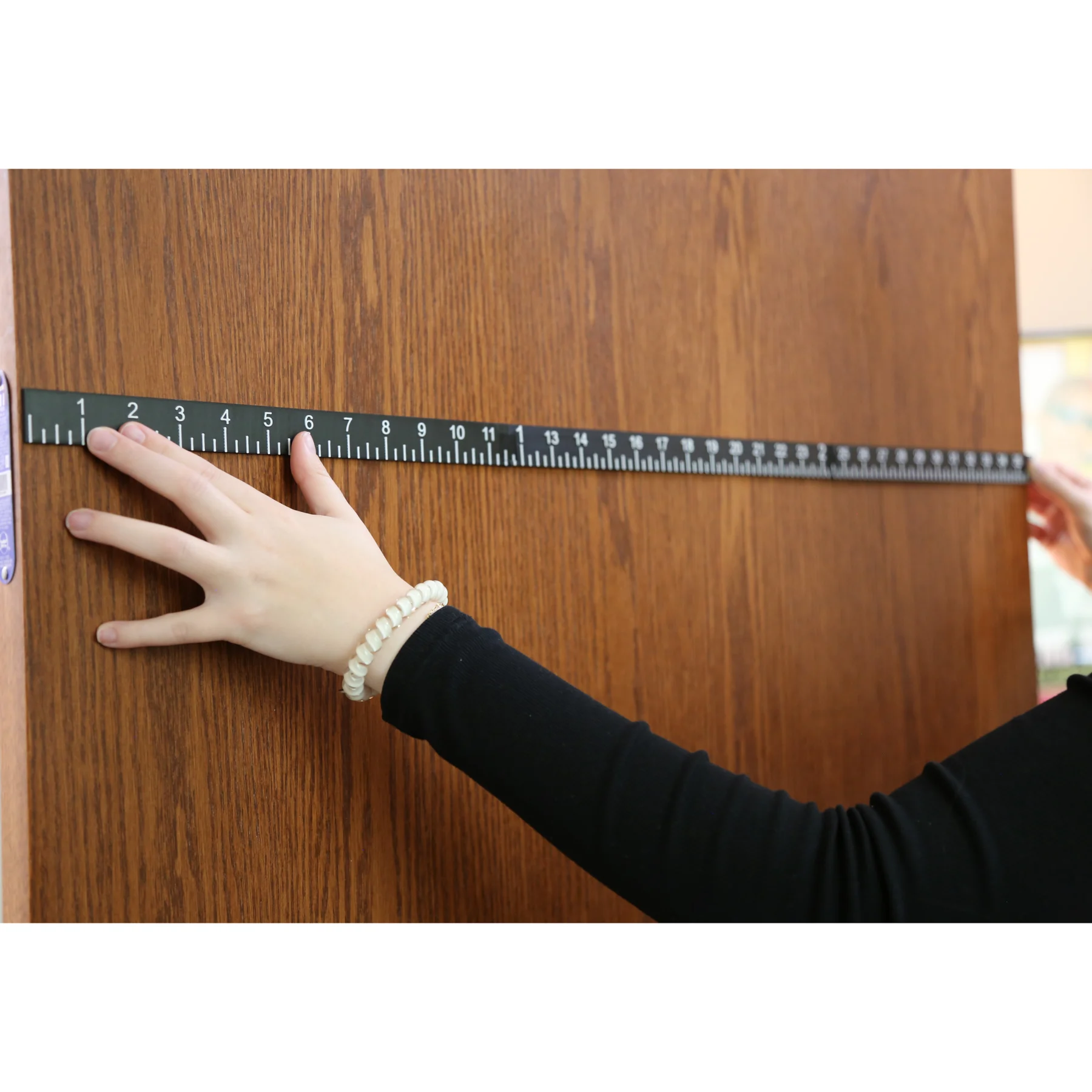 Someone measure a door using a braille ruler yard stick