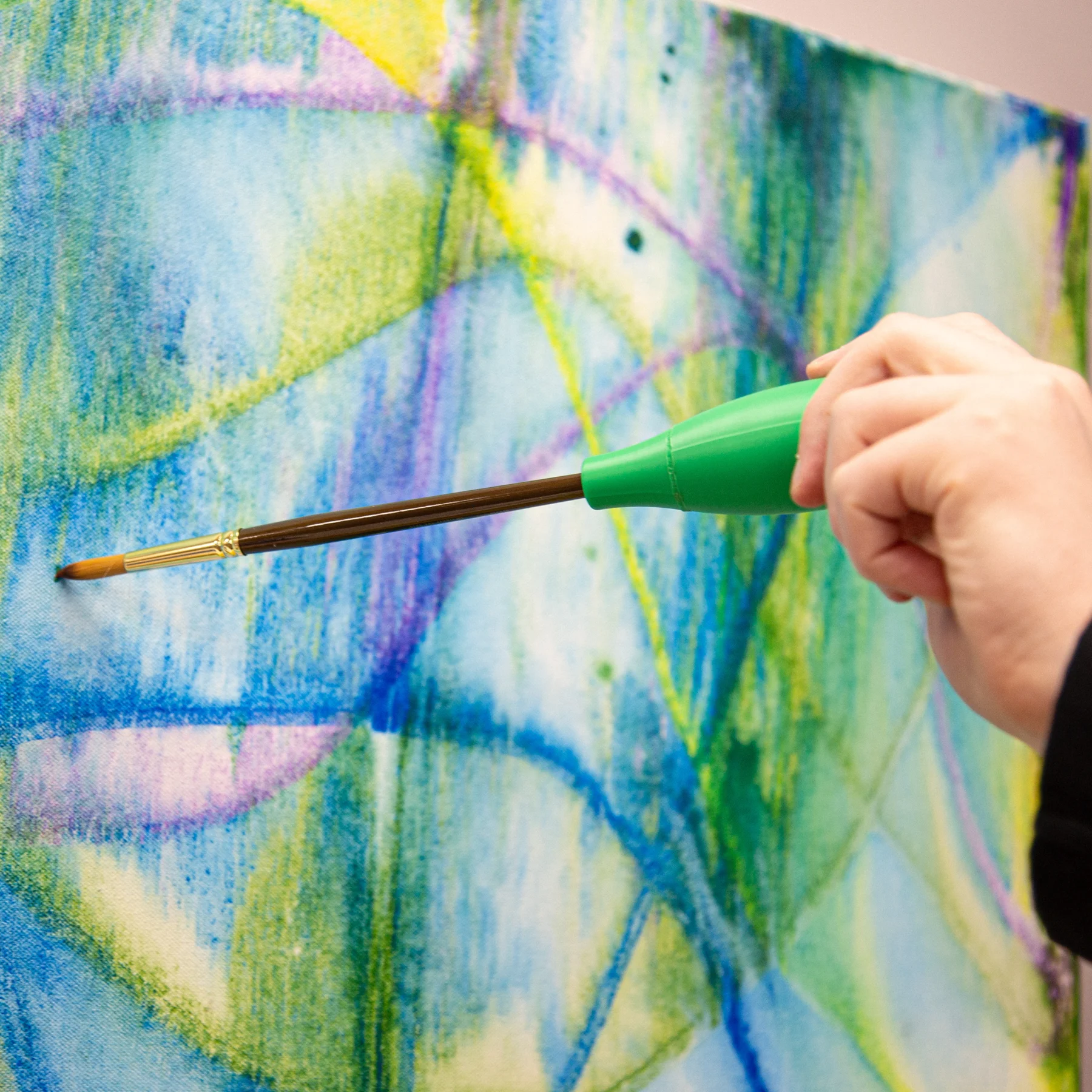 Person using a paint brush holder on a canvas