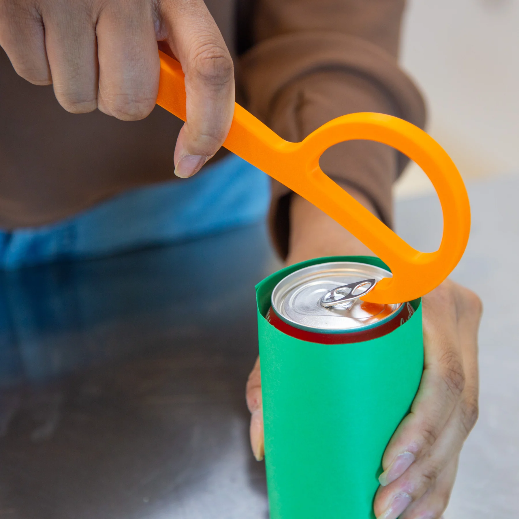 Woman using Pop Tab Can Opener to open can of soda