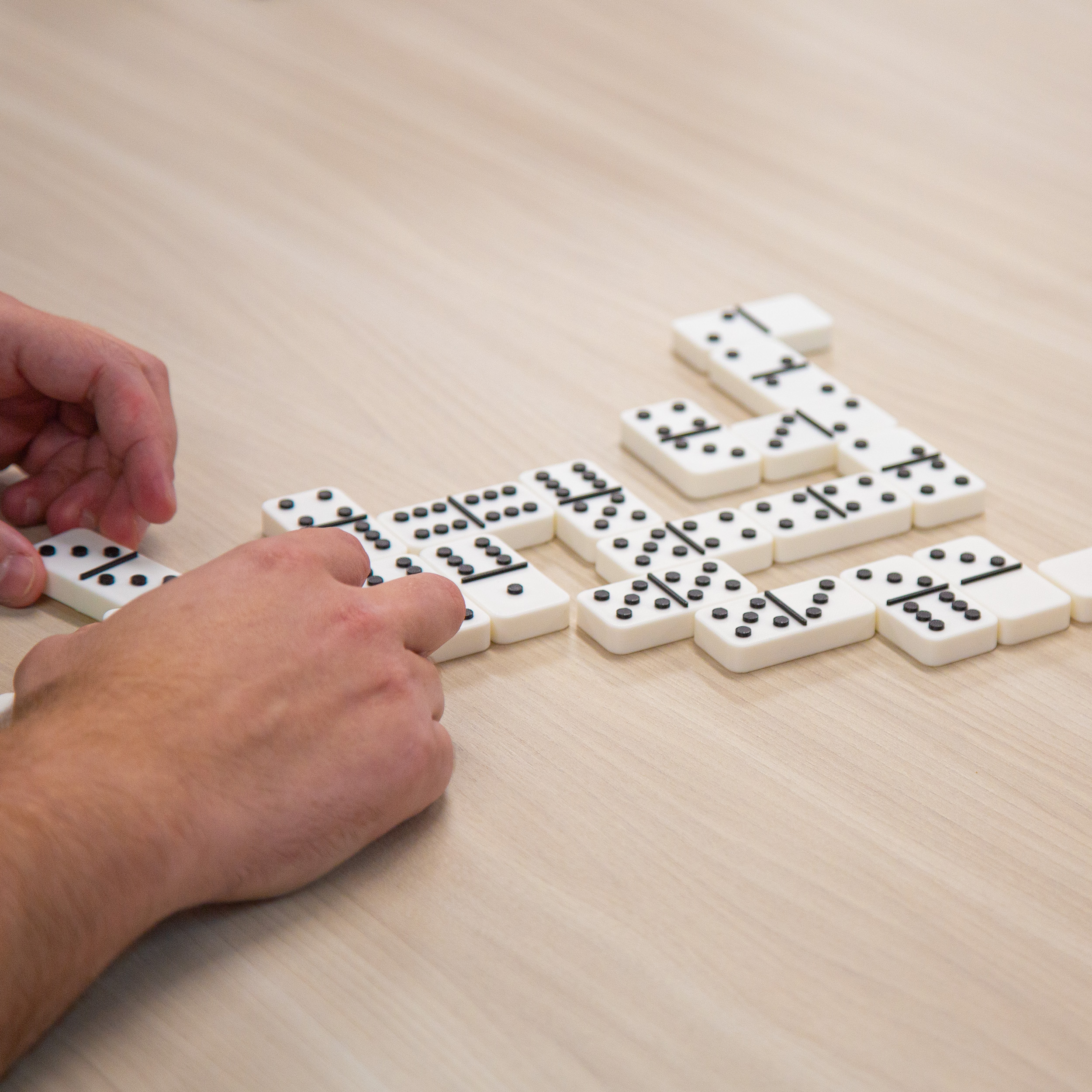 Man feeling tactile dominos, arranging the dominos on the table